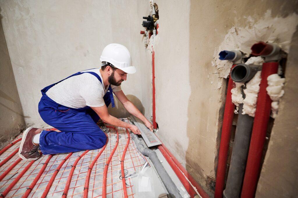 Instalator wykonujący instalację ogrzewania podłogowego w pomieszczeniu