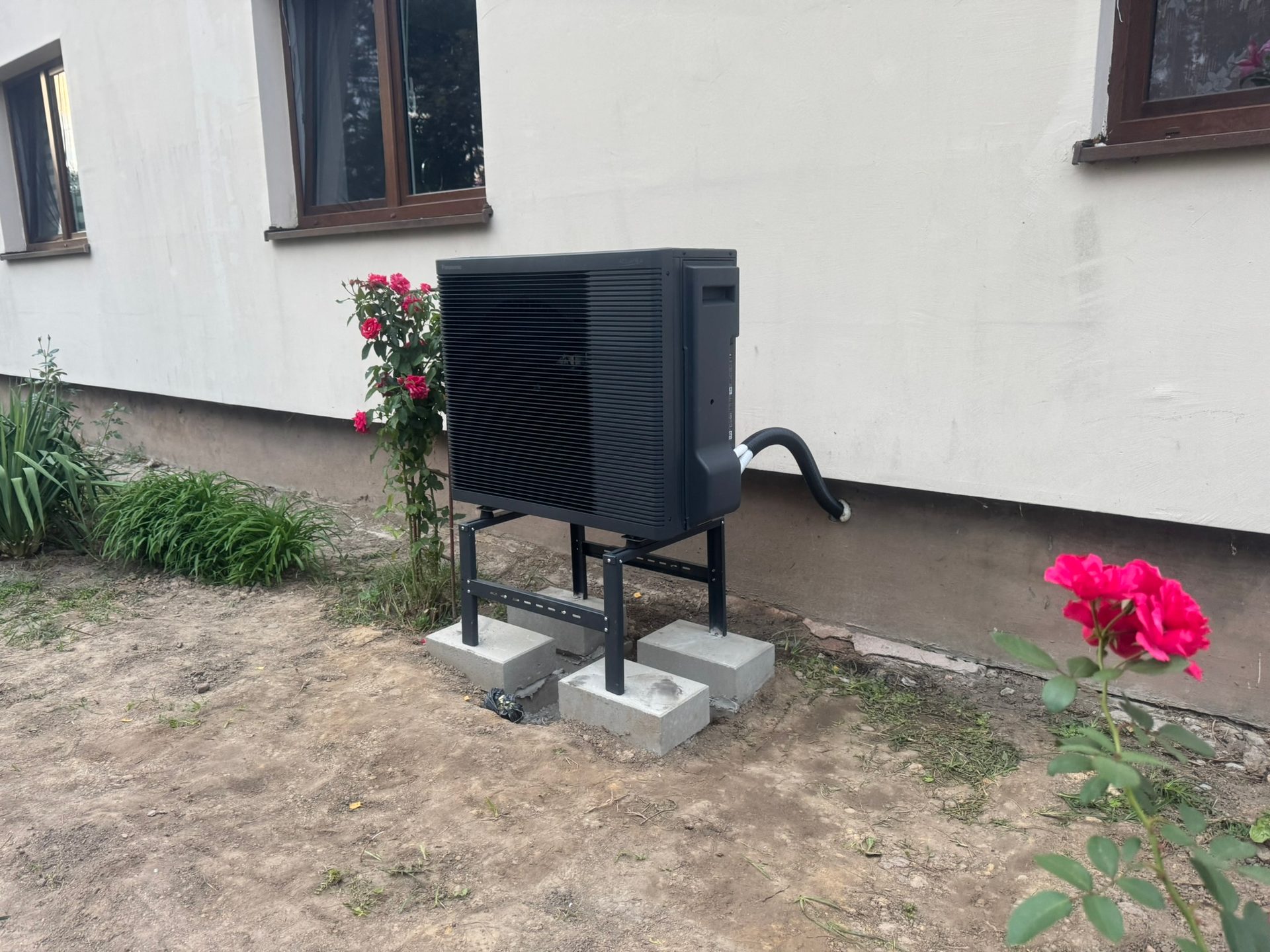 Pompa ciepła powietrze-woda na stelażu montażowym w ogrodzie